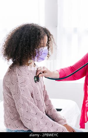 Giovane ragazza biraciale al dottore che ha ascoltato il battito cardiaco Foto Stock