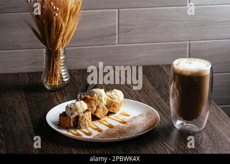 torta di mele con palle di gelato. caffè latte in un bicchiere trasparente Foto Stock