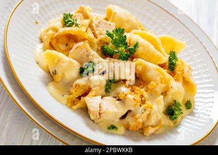 pasta di pollo e conchiglie cheesy e cremosa cuocere in ciotola bianca su tavolo bianco, vista orizzontale dall'alto, primo piano Foto Stock