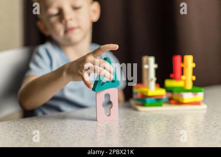 Un ragazzo sta giocando un giocattolo educativo puzzle. Primo piano di parti in legno. Foto Stock