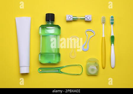 Composizione a posa piatta con detergenti per lingua e prodotti per la cura dei denti su fondo giallo Foto Stock