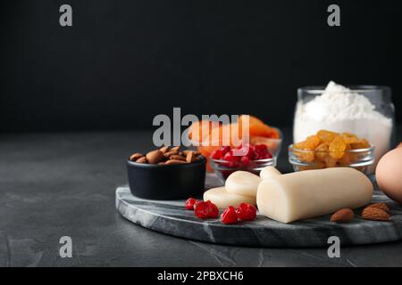 Marzapane e altri ingredienti per Stollen fatto in casa su tavolo grigio su sfondo scuro. Cottura del tradizionale pane di Natale tedesco Foto Stock