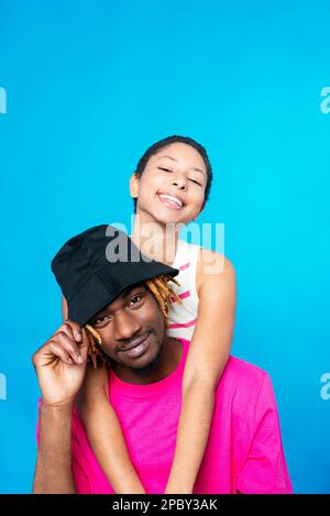 Ha deliziato giovane etnica millenario con capelli scuri sorridendo felicemente e guardando la macchina fotografica mentre abbraccia positivo afro-americano ragazzo agai Foto Stock