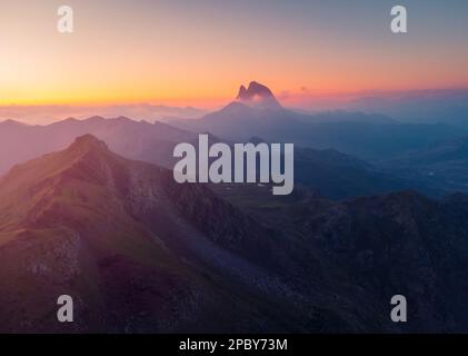 Spettacolare scenario di massiccio pendio roccioso Anayet montagna contro il cielo tramonto sul maestoso crinale e lago nei Pirenei Foto Stock