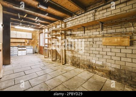 Interno di vecchio garage shabby con pareti in mattoni e scaffali vicino armadi illuminati da lampade Foto Stock