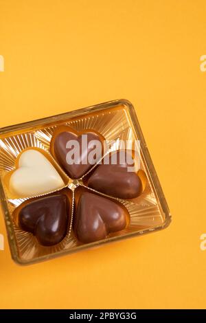 foto quattro pezzi di cioccolato a forma di cuore su sfondo giallo Foto Stock