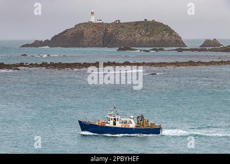 La nave di supporto per le immersioni 'Boy Brendan', gestita da Seawwide Services, passa davanti al faro di Round Island al largo di Tresco, Isole di Scilly, Cornovaglia, Regno Unito Foto Stock