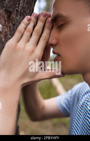 Pregare bello uomo foresta concetto. Foto Stock