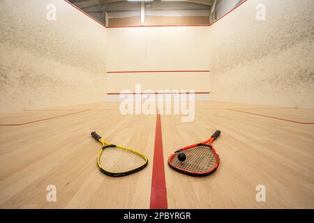 Campo da squash vuoto con vista ultra-grandangolare. Racket e palla a terra, non persone. Foto Stock