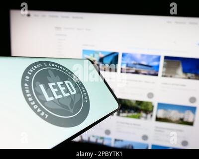 Cellulare con logo di certificazione US verde edificio LEED sullo schermo di fronte al sito web. Messa a fuoco sul lato destro del display del telefono. Foto Stock