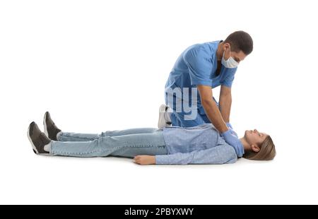 Medico in uniforme praticando il primo soccorso su donna su sfondo bianco Foto Stock