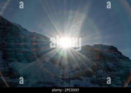 Eigergletscher, Canton Berna (Svizzera), 11 febbraio 2023 Sun sorge dietro una vetta delle alpi innevate Foto Stock