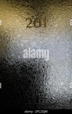 Vetro crepato nella finestra della porta dell'ufficio con numeri e illuminazione soffusa. Foto Stock