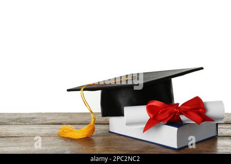 Cappello di laurea, libro e diploma su tavolo di legno su sfondo bianco Foto Stock