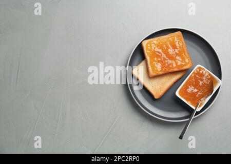 Toast e inceppamento arancione sul tavolo grigio, vista dall'alto. Spazio per il testo Foto Stock