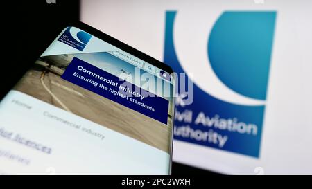 Smartphone con pagina Web della British Regulator Civil Aviation Authority (CAA) sullo schermo davanti al logo. Messa a fuoco in alto a sinistra del display del telefono. Foto Stock