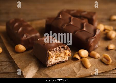 Barrette di cioccolato con caramello, noci e torrone sul tavolo, primo piano Foto Stock