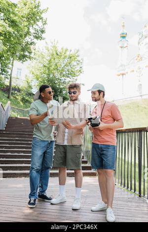 Tutta la lunghezza dei turisti interracial che guardano la mappa della città mentre si levano in piedi sulle scale vicino alla chiesa di St Andrews sullo sfondo sfocato, immagine di scorta Foto Stock