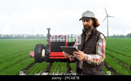 Un agricoltore con tablet digitale controlla un trattore autonomo in un'azienda agricola intelligente Foto Stock