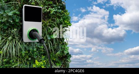 Stazione di ricarica per auto elettriche su una parete verde degli impianti Foto Stock