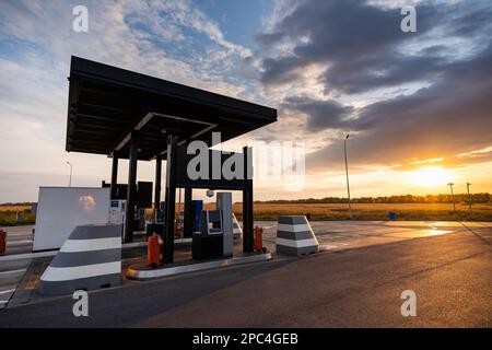 Moderna stazione di servizio self-service sullo sfondo di un suggestivo cielo al tramonto Foto Stock