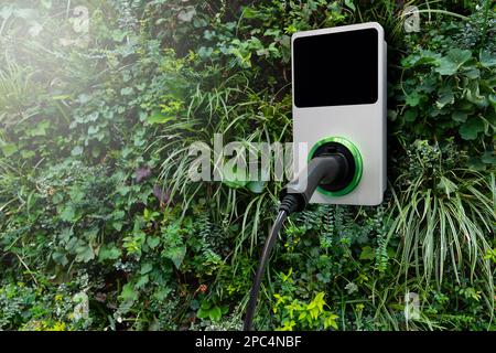 Stazione di ricarica per auto elettriche su una parete verde degli impianti Foto Stock