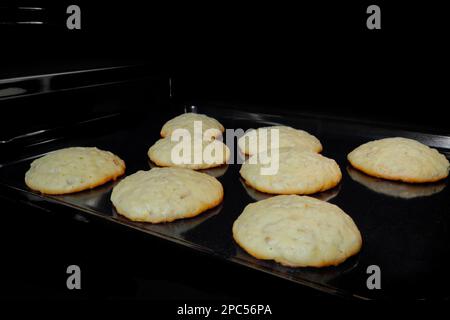 Cottura di otto biscotti croccanti di farina d'avena su lamiera in forno Foto Stock