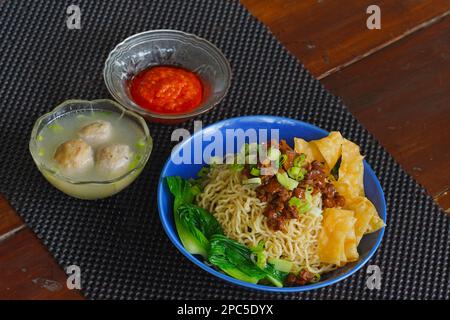 Mie Ayam o tagliatelle di pollo indonesiane con brodo servito in ciotola con salsa di peperoncino. Foto Stock