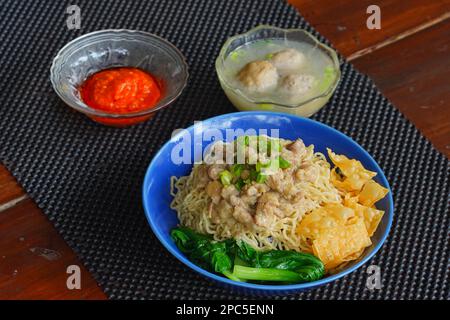 Mie Ayam o tagliatelle di pollo indonesiane con brodo servito in ciotola con salsa di peperoncino. Foto Stock