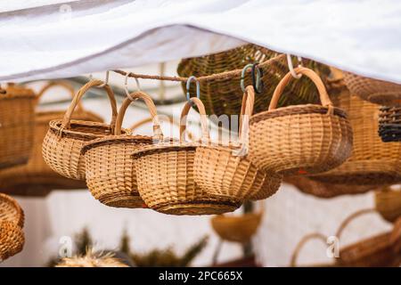 Gruppo di cestini di vimini vuoti appesi in vendita in un mercato di strada o in una fiera tradizionale Foto Stock