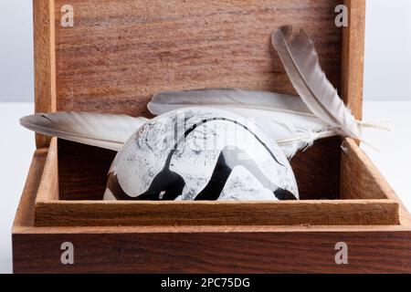 sfera strutturata in vetro bianco e nero all'interno di una scatola di legno isolata su sfondo bianco Foto Stock