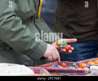 Shopping di Pasqua. I turisti guardano le uova di Pasqua in vendita in un mercato agricolo a Praga. Le colorate uova dipinte sono una delle tradizionali decorazioni pasquali Foto Stock