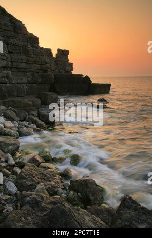 Vista delle onde sulla spiaggia rocciosa e vecchia cava sulle scogliere al tramonto, Winspit Bay, vicino Worth Matravers, Isola di Purbeck, Dorset, Inghilterra, Regno Unito, Foto Stock