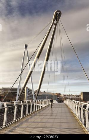 Uomo in bicicletta che attraversa il ponte pedonale sul fiume, il ponte pedonale di Newport City, il fiume Usk, Newport, Galles del Sud, Galles Foto Stock