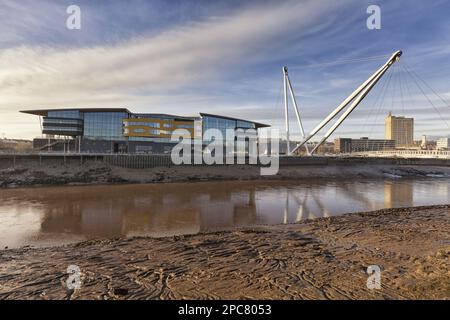 Vista del fiume di marea, dell'edificio sul lungomare e del ponte pedonale, della Newport University, del ponte pedonale di Newport City, del fiume Usk, di Newport, Galles del Sud, Galles Foto Stock