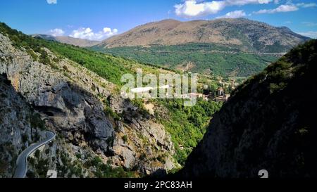 ripresa aerea di una splendida casa all'interno di una scogliera sulle montagne italiane in una soleggiata giornata estiva, vista dall'occhio degli uccelli, punto di riferimento e natura. Foto Stock