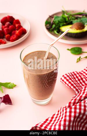 Colazioni salutari, frullati a base di fragole congelate, avocado e banana, proteine della piselli e semi di lino, foglie di insalata, frullati in un bicchiere Foto Stock