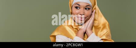 Bella donna multirazziale in hijab guardando lontano isolato su verde, banner, immagine stock Foto Stock