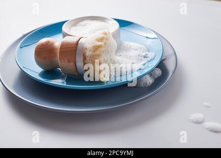 Sapone solido per il lavaggio delle stoviglie, ricoperto di schiuma. Stile di vita senza sprechi. Pile di piatti con spazzola rotonda in bambù sisal per la pulizia della cucina Foto Stock