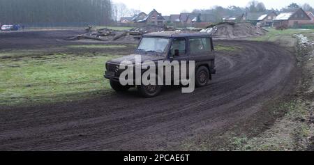 Itterbeck, Germania Marzo 12 2023 Una jeep Mercedes completamente sporca che guida su un binario fuoristrada attraverso il fango. È una Mercedes-Benz Classe G W460 Foto Stock