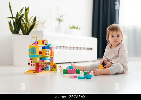 adorabile bambino che gioca con blocchi da costruzione multicolore sul pavimento Foto Stock