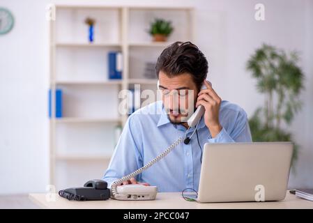 Giovane operatore del call center che lavora alla sua scrivania Foto Stock