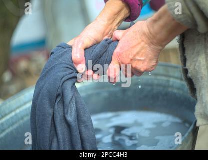 Donna che strizzava i vestiti dopo il lavaggio Foto Stock