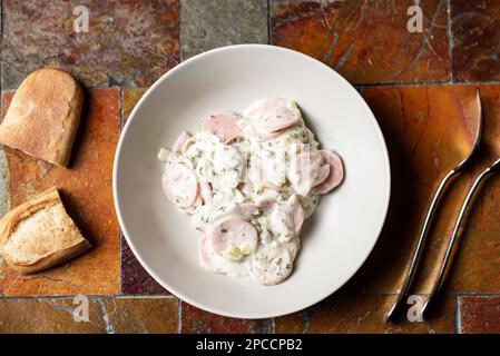 Insalata di panna acida e salsiccia verde su piatto con pane. Insalata semplice su piatto. Foto Stock