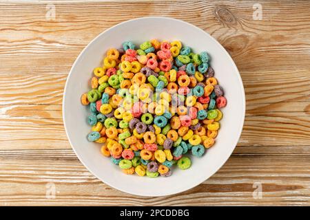 Variopinti anelli per la colazione pile, anse di frutta, anelli di cereali fruttati, cereali di mais colorati su sfondo di legno Foto Stock