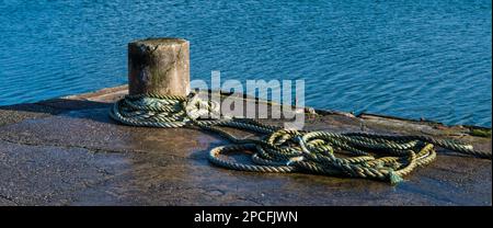 Scena nautica di un rustico tondino di cemento e corda in un molo a Carnlough Harbour, Irlanda del Nord Foto Stock