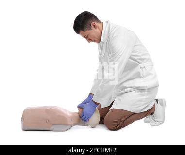 Medico in uniforme praticando il primo soccorso sul manichino su sfondo bianco Foto Stock