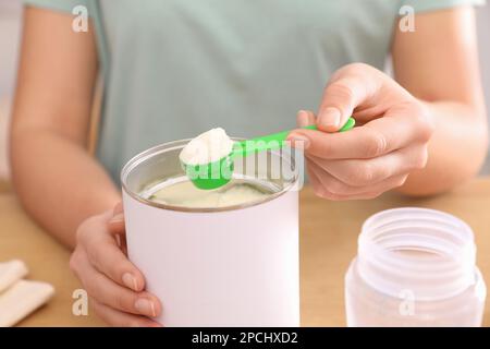 Donna con latte in polvere per neonati a tavola, primo piano. Preparazione  del latte per bambini Foto stock - Alamy