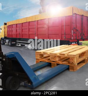 Moderno carrello elevatore manuale con pallet in legno vicino al camion all'aperto nelle giornate di sole Foto Stock