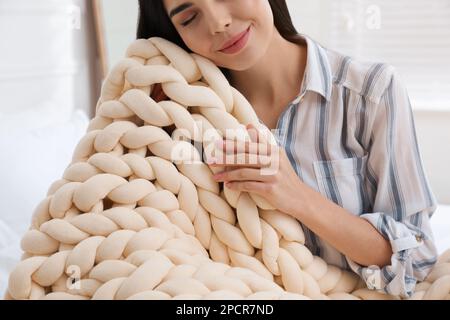 Giovane donna con coperta a maglia a casa, primo piano Foto Stock